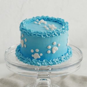 Sky blue dog birthday cake with white frosting paw prints