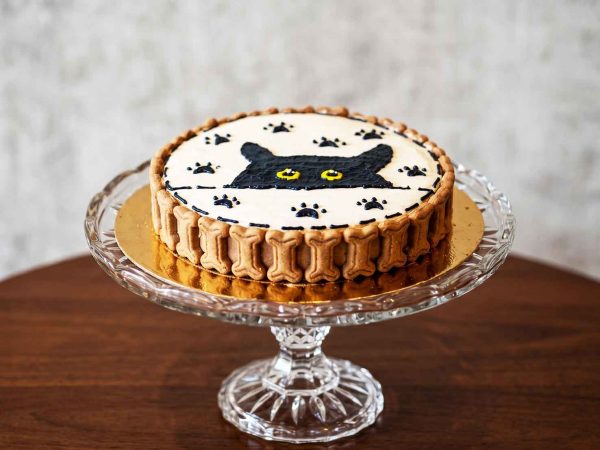 White pet cake with a peeking black cat face, paw prints, and a bone biscuit border.
